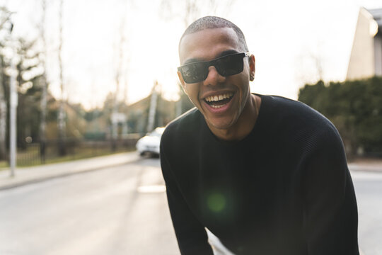 handsome Afro-American boy with black sunglasses looking to camera dda laughing, medium shot outdoors. High quality photo