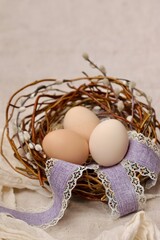 Wielkanocne ozdoby - jajka w gniazdku na lnianym obrusie. Rustykalne symbole wiosennych świąt na świątecznym stole. - obrazy, fototapety, plakaty