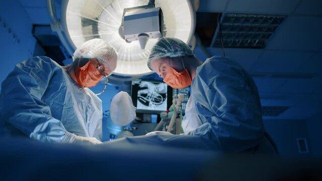 A veterinarian highly focused on an operation as a nurse assists him. They are performing a surgery and need to be steady. High quality 4k footage. 