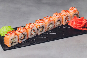 Maki Sushi Rolls with salmon on black stone on dark background. With ginger and wasabi. Sushi menu....
