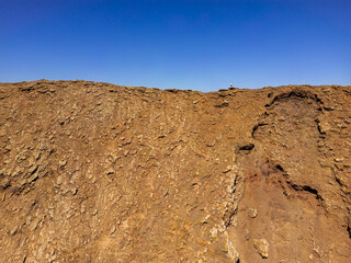 Dramatic image of a person standing on the ridge of the steep sided volcanic crater of Las Calderas volcano near Corralejo in Fuerteventura Spain