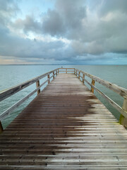 Empty wooden pier with dramatic sky and calm water