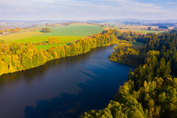 Impressive colorful autumn landscape of trees in park and river, view from drone