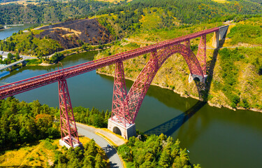 Scenic drone view of parabolic arched framework of railway bridge Viaduc de Garabit across river...