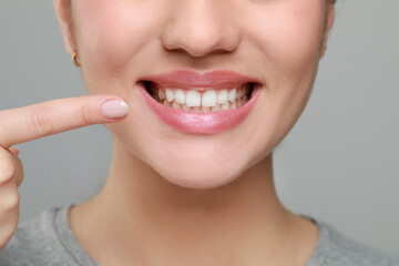 Woman showing healthy gums on grey background, closeup