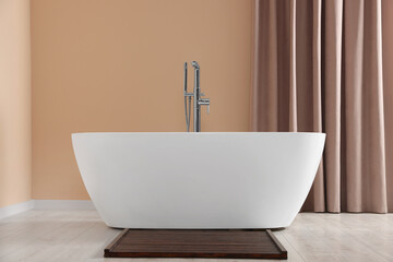 Obraz na płótnie Canvas Stylish bathroom interior with ceramic tub near beige curtains