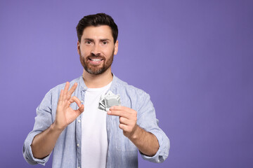 Man with condoms showing ok gesture on purple background, space for text. Safe sex
