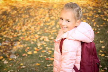 Cute little girl with backpack in park on autumn day. Space for text