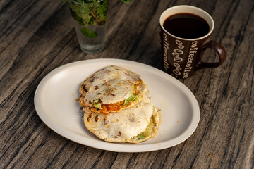 gorditas de maiz con carne en salsa roja y verde, comida mexicana callejera, artesanal, con cafe de fondo en mesa de madera rustica