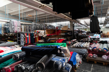 Interior of an industrial warehouse with fabric rolls samples. Small business textile colorful warehouse.