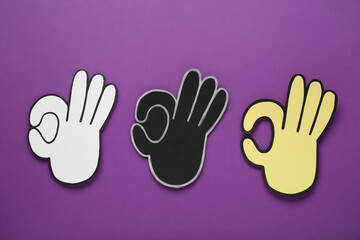 Obraz premium Paper cutouts of Okay hand gesture on purple background, top view