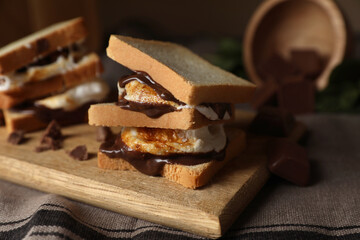 Delicious marshmallow sandwiches with bread and chocolate on wooden board, closeup. Space for text