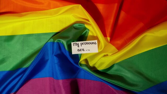 Stop motion of MY PRONOUNS ARE Neo pronouns concept. Rainbow flag with paper notes text gender pronouns hie, e, ne, xe, ze, tey. Non-binary people rights transgenders. Lgbtq community support assume