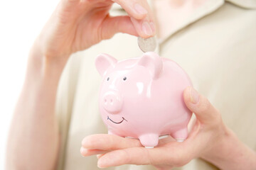 貯金箱にコインを入れる中年女性　白背景　顔無し