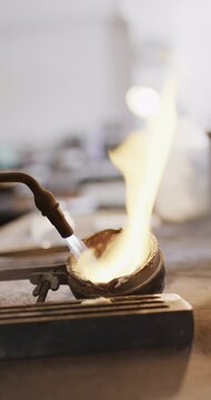 Vertical video of close up of melting metal with blowtorch in workshop in slow motion