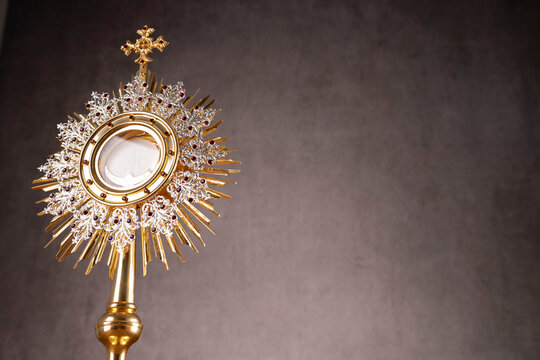Catholic religion concept. Easter.The monstrance and golden chalice on gray background. 