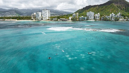 Surfer in the blue transparent ocean in Hawaii from above, aerial drone shot.