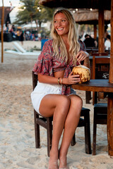 Woman drinking coconut water on the beach in Mexico