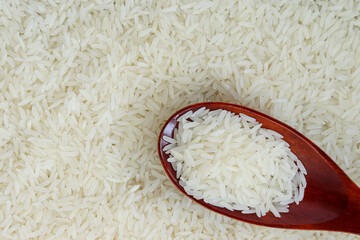 White rice, jasmine rice, on a wooden spoon, placed on top of the grain.