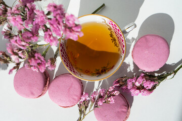 A cup of tea with almond cookies on a white background. Pink pasta and a mug. Flowers in a vase....