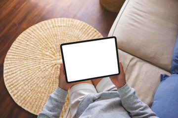 Top view mockup image of a woman holding digital tablet with blank desktop screen on sofa at home