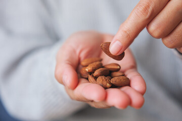Closeup image of hands holding and picking up an almonds