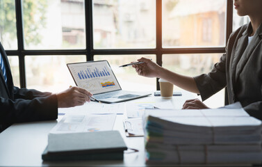 Team of business people is calculating with a calculator and discussing to record company financial growth statistics using graphs. The chart is a reference for auditing and analyzing the summary.