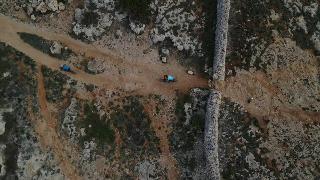 Cyclists push through a tough section of mountain bike race event over rocks and stone walls in Spain.