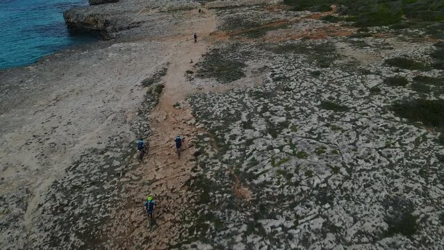 Mountain bike riders struggle to get over the rocks mid way through event on Menorca, Spain.