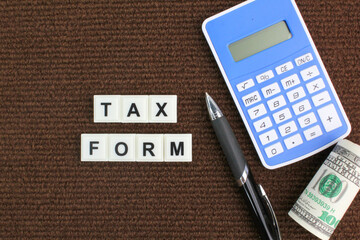 pen, calculator and paper money with the word tax form. tax payment concept