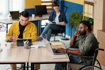 Pensive businessman with disability reading article or report on laptop screen