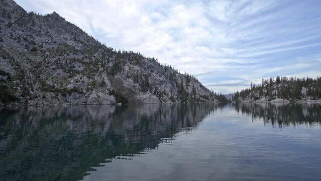 Panning view of beautiful alpine lake surrounded by rocky mountain landscape