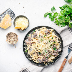 Prepared pasta with mushrooms with parsley and cheese on grey table background, top view. Healthy cooking and eating. Italian food concept