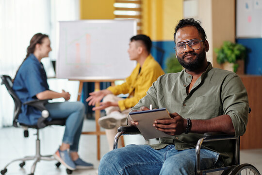 Portrait of positive Indian entrepreneur writing down plan for the days