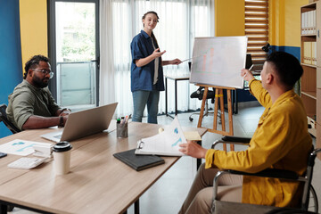 Fototapeta premium Smiling female entrepreneur answering questions of colleagues at meeting