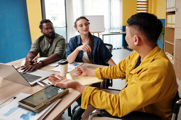 Businessman answering questions of colleagues after showing project presentation