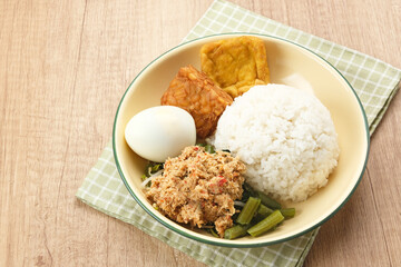 Nasi Gudangan, rice served with various vegetable with grated coconut seasoned and various side dishes. Indonesian food
