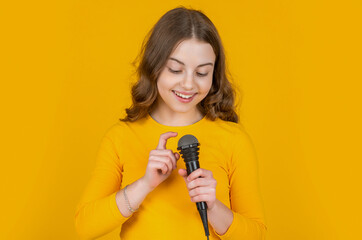 happy teen girl check mic on yellow background