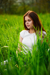 portrait of a joyful cute woman sitting in the grass