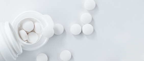 Pharmacy theme, bottle and scattered white round pills on table, top view, flat lay.