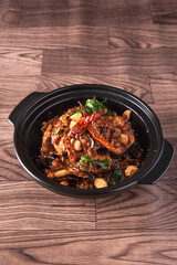 local cook live fresh catfish meat with spicy red dry chili asam sauce in big black claypot on wood table asian Chinese banquet halal seafood steamboat menu 