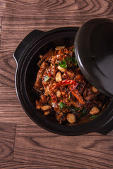 local cook live fresh catfish meat with spicy red dry chili asam sauce in big black claypot on wood...