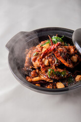 local cook live fresh catfish meat with spicy red dry chili asam sauce in big black claypot on wood table asian Chinese banquet halal seafood steamboat menu 