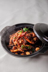 local cook live fresh catfish meat with spicy red dry chili asam sauce in big black claypot on wood table asian Chinese banquet halal seafood steamboat menu 