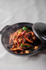 local cook live fresh catfish meat with spicy red dry chili asam sauce in big black claypot on wood table asian Chinese banquet halal seafood steamboat menu 