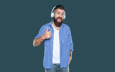 surprised bearded man listen to music in headphones. point finger