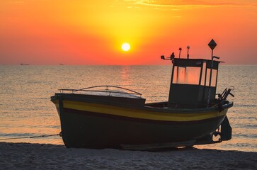 Colorful morning landscape by the sea. Beautiful boat on the beach with the rising sun. Photo taken in Gdynia, Poland.