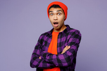 Young sad man of African American ethnicity wear casual shirt orange hat look camera with opened mouth hold hands crossed folded isolated on plain pastel light purple color background studio portrait.
