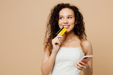 Happy young woman bride wear white wedding dress posing hold mobile cell phone credit bank card...