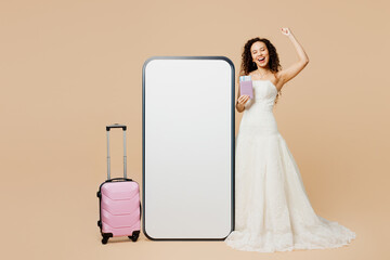 Traveler young woman bride wears wedding dress hold passport ticket big blank screen mobile cell...